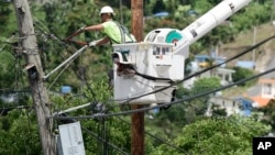 A worker from the Cobra Energy Co., contracted by the Army Corps of Engineers, installs power lines in the Barrio Martorel area of Yabucoa, a town where many residents continue without power in Puerto Rico, May 16, 2018.