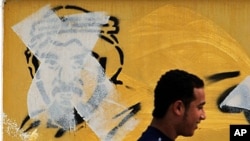 A Bahraini man in Manama passes by an image of Shiite leader Hassan Meshaima, crossed out with a paint roller by authorities, February 24, 2011