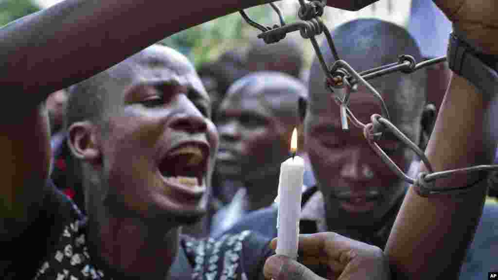 A Kenyan student wears mock chains and another holds a candle as they march with others in memory of the victims of the Garissa college attack and to protest what they say is a lack of security, in downtown Nairobi, le 7 avril 2015.