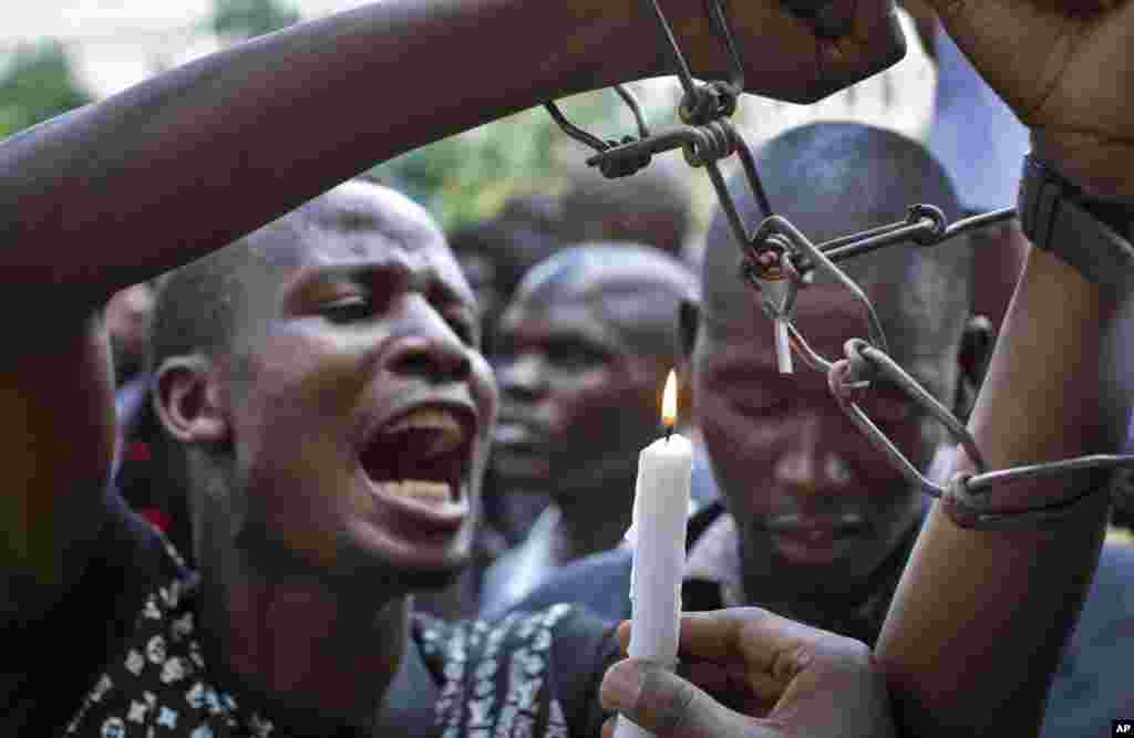 A Kenyan student wears mock chains and another holds a candle as they march with others in memory of the victims of the Garissa college attack and to protest what they say is a lack of security, in downtown Nairobi, April 7, 2015.