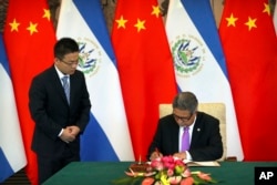 FILE - El Salvador's Foreign Minister Carlos Castaneda, right, signs documents at a signing ceremony to mark the establishment of diplomatic relations between El Salvador and China at the Diaoyutai State Guesthouse in Beijing, China, Aug. 21, 2018.