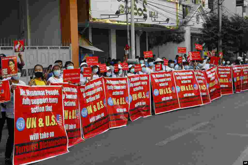 Protesters hold banners during an anti-coup rally in front of the Myanmar Economic Bank in Mandalay.