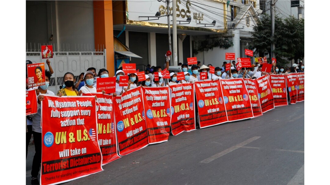 Người biểu tình với biểu ngữ ghi dòng chữ: "Chúng tôi, nhân dân Myanmar, hoàn toàn ủng hộ mọi hành động mà LHQ và Hoa Kỳ có thể đề ra chống "Độc tài Khủng bố" trong cuộc biểu tình chống đảo chính quân sự. Ảnh chụp trước Ngân hàng Kinh tế Myanmar ở Mandalay, Myanmar, ngày 15/2/2021. AP