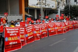 Người biểu tình với biểu ngữ ghi dòng chữ: "Chúng tôi, nhân dân Myanmar, hoàn toàn ủng hộ mọi hành động mà LHQ và Hoa Kỳ có thể đề ra chống "Độc tài Khủng bố" trong cuộc biểu tình chống đảo chính quân sự. Ảnh chụp trước Ngân hàng Kinh tế Myanmar ở Mandalay, Myanmar, ngày 15/2/2021. AP