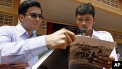 Dy Khamboly, left, a staff member at the Documentation Center of Cambodia, helps a student read his book "A History of Democratic Kampuchea" in Anlong Veng, in Oddar Meanchey province, file photo. 