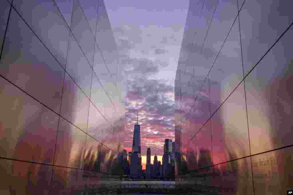 Framed through the Empty Sky Memorial in Jersey City, New Jersey, sunrise lights up the sky behind the New York City skyline.