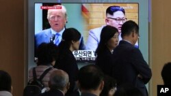 People pass by a TV screen showing file footage of U.S. President Donald Trump, left, and North Korean leader Kim Jong Un during a news program at the Seoul Railway Station in Seoul, South Korea, May 18, 2018.