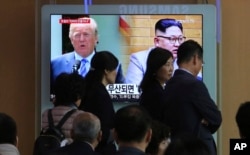 People pass by a TV screen showing file footage of U.S. President Donald Trump, left, and North Korean leader Kim Jong Un during a news program at the Seoul Railway Station in Seoul, South Korea, May 18, 2018.