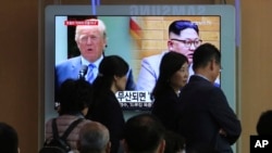 Para pengunjung melewati layar televisi yang sedang menampilkan gambar Presiden AS Donald Trump (kiri) dan Pemimpin Korea Utara Kim Jong Un di Stasiun Kereta Seoul di Seoul, Korea Selatan, 18 Mei 2018.