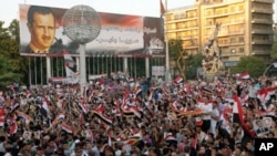 A handout picture released by the Syrian Arab News Agency (SANA) shows hundreds of Syrians waving their national flag during a rally, July 28, 2011