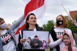 FILE - Belarus opposition leader Sviatlana Tsikhanouskaya holds a picture of her husband Syarhei Tsikhanouski during a "Belarus support day" protest in Vilnius, Lithuania, May 29, 2021.