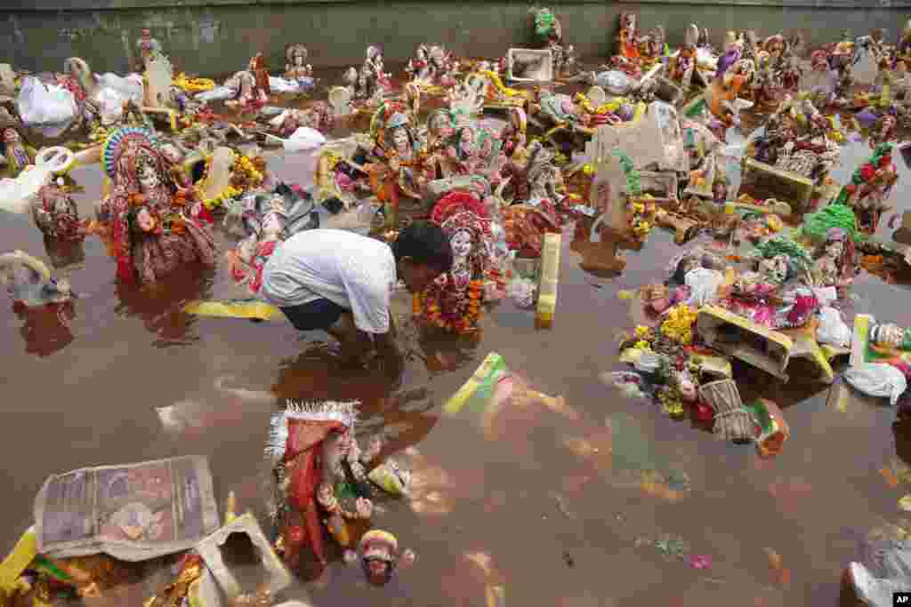 A boy searches for reusable items amid idols of Hindu goddess Dashama lying in river Sabarmati after the end of Dashama festival in Ahmadabad, India.