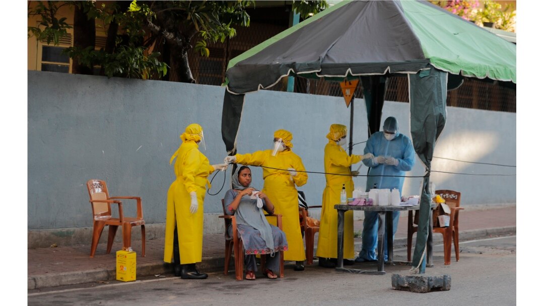 Pejabat kesehatan Sri Lanka melakukan tes usap saat mereka melakukan skrining acak untuk COVID-19 di area terkunci di Kolombo, Sri Lanka, Senin, 20 April 2020. (Foto: AP)
