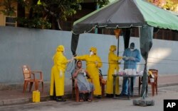 Pejabat kesehatan Sri Lanka melakukan tes usap saat mereka melakukan skrining acak untuk COVID-19 di area terkunci di Kolombo, Sri Lanka, Senin, 20 April 2020. (Foto: AP)