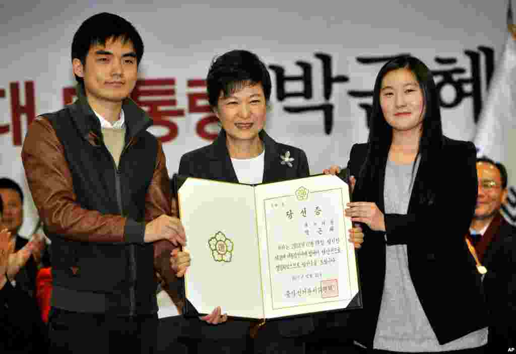 South Korea&#39;s president-elect Park Geun-hye, center, poses with an official certificate stating her election victory, Seoul, December 20, 2012. 