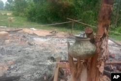 In this image provided by Myanmar Witness, which is undated and unverified but matches AP reporting and eyewitness testimony, a burned structure with household goods is seen outside Taung Pauk village in Kani township in Myanmar's Sagaing region.