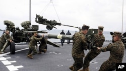 U.S. Marines assigned to the 31st Marine Expeditionary Unit haul a 155 mm Howitzer onto the flight deck of the forward-deployed amphibious dock landing ship USS Germantown in Okinawa, Japan, February 2, 2012.