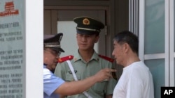 A Chinese police officer points as he speaks to a Chinese man held at a security checkpoint on Tiananmen Square in Beijing Wednesday, June 4, 2014.