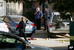 Fresno police Investigator Brooke Passmore, left, works on the driveway on Lamona Avenue where a shooting took place at a house party which involved multiple fatalities and injuries in Fresno, Calif., Monday, Nov. 18, 2019. (AP Photo/Gary Kazanjian)