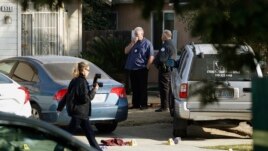 Fresno police Investigator Brooke Passmore, left, works on the driveway on Lamona Avenue where a shooting took place at a house party which involved multiple fatalities and injuries in Fresno, Calif., Monday, Nov. 18, 2019. (AP Photo/Gary Kazanjian)