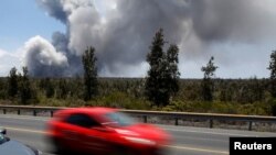 As a car dashes by, an ash plume rises from the Halemaumau Crater on Kilauea's summit, near Volcano, Hawaii, May 25, 2018. 