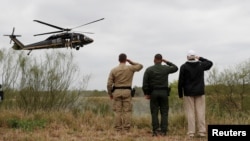 President Donald Trump salutes a U.S. Border Patrol helicopter with U.S. Border Patrol agents as it flies over the Rio Grande River during his visit to the U.S.- Mexico border in Mission, Texas, Jan. 10, 2019.