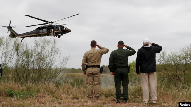 特朗普總統在視察德克薩斯州的美-墨邊境時，向一架飛越格蘭德河的美國邊境巡邏直升機敬禮。(2019年1月10日)