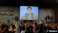Lebanon's Hezbollah leader Sayyed Hassan Nasrallah addresses his supporters from a screen during a rally to commemorate Hezbollah Wounded Veterans Day in Beirut suburbs, Lebanon, June 14, 2013.