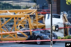 Emergency crews work at the scene of a construction crane collapse, April 27, 2019. The crane collapsed near the intersection of Mercer Street and Fairview Avenue pinning cars underneath it near Interstate 5.