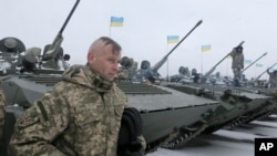 A Ukrainian serviceman stands near armored vehicles during a ceremony with Ukrainian President Petro Poroshenko to mark the delivery of more than 100 pieces of military equipment to the Ukrainian armed forces, near Zhitomir, Ukraine, Jan. 5, 2015.