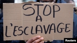 A man holds a placard with the message "Stop slavery" as he attends a protest against slavery in Libya outside the Libyan Embassy in Paris, France, Nov. 24, 2017.