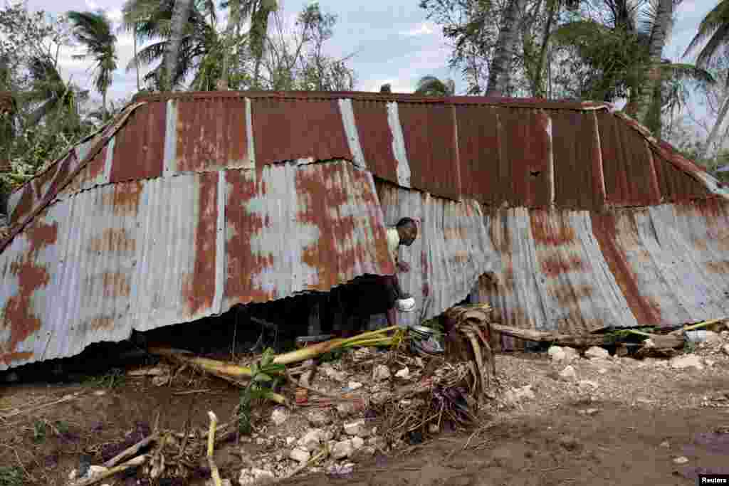 Seorang perempuan keluar dari rumahnya yang hancur oleh Badai Matthew di Cavaillon, Haiti (6/10).&nbsp;(Reuters/Andres Martinez Casares)