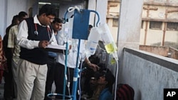 FILE - A doctor tends to alcohol poisoning patients who drank bootleg alcohol in this Dec. 15, 2011, photo. Each year, hundreds of people die in India because of illegal alcohol.