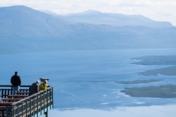 FILE - Tourists visit Mount Nuolja overlooking Abisko in northern Sweden on Aug. 26, 2021, where scientists and researchers are investigating the impact on climate change on many aspects of the Arctic.