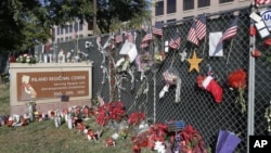 FILE - Flowers and American flags honoring the 14 victims of the Dec. 2, 2015, terror attack in San Bernardino, California, Dec. 29, 2015. Apple refused to help the FBI unlock an iPhone belonging to one of the assailants.