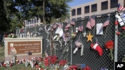 FILE - Flowers and American flags honoring the victims of the Dec. 2, 2015, terror attack at the Inland Regional Center are seen outside the complex in San Bernardino, California, Dec. 29, 2015.