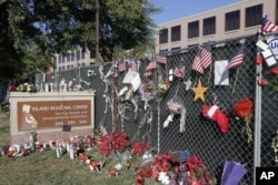 FILE - Flowers and American flags honoring the victims of the Dec. 2, 2015, terror attack at the Inland Regional Center are seen outside the complex in San Bernardino, California, Dec. 29, 2015.