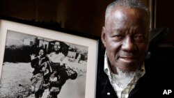 FILE - South African photographer Sam Nzima poses with his iconic photo showing 13-year-old Hector Pieterson being carried after being shot dead by apartheid police during the 1976 Soweto uprising, in Pretoria, April 27, 2011.