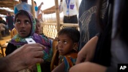 A newly arrived Rohingya Muslim boy looks as a UNHCR volunteer takes the measurement after their arrival at the transit camp at Balukhali refugee camp 50 kilometres (32 miles) from Cox's Bazar, Bangladesh, Sunday, Jan. 14, 2018.