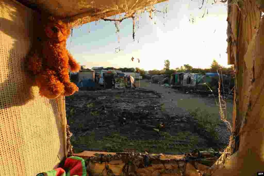 A teddy bear left behind my migrants hangs at the demolished "Jungle" migrant camp in Calais in northern France.