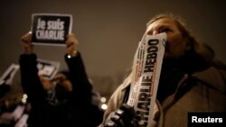 A man holds a copy of weekly satirical magazine Charlie Hebdo to pay tribute during a gathering at the Place de la Republique in Paris Jan. 7, 2015.