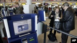 FILE - Travelers use an automated passport control kiosk at John F. Kennedy Airport in New York.