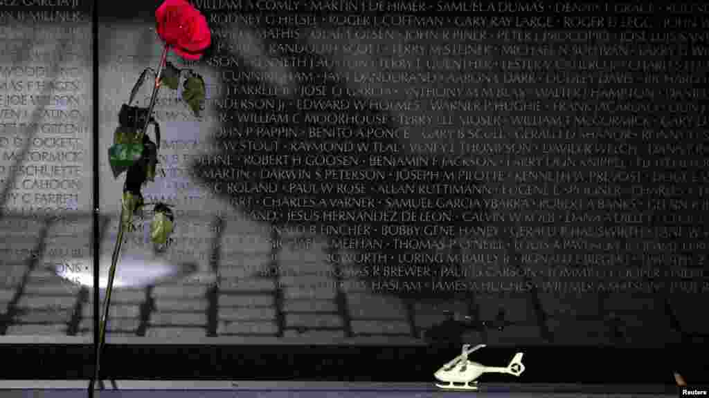 A rose and a toy helicopter are seen next to the Vietnam Veterans Memorial wall during Veterans day in Washington, D.C.