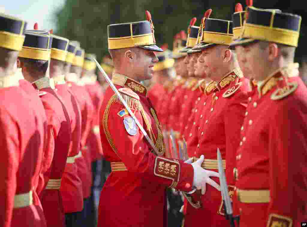 An honor guard soldier adjusts the outfit of a colleague before a welcoming ceremony for NATO Secretary General Jens Stoltenberg in Bucharest, Romania.