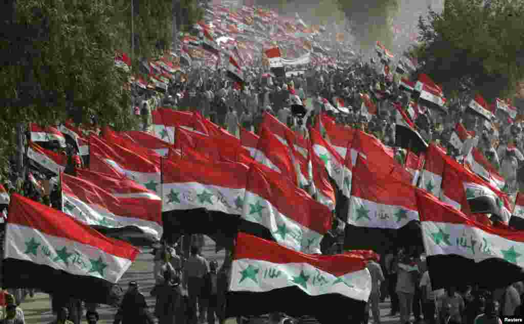 تظاهرکنندگان در طی تظاهرات ضدآمریکایی پرچم های عراق را به پرواز درمی آورند. مقتدی صدر روحانی بانفوذ در نجف در چهارمین سالگرد سقوط&nbsp; بغداد برای برگزاری تظاهرات فراخوان داده بود. ٩ آوریل سال ٢٠٠٧. 