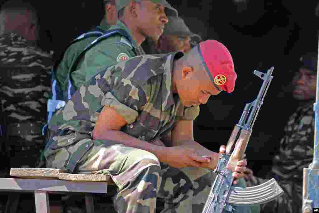 A soldier looks at his telephone as he and others provide security outside a polling station in Antananarivo, Madagascar, Oct. 25, 2013.