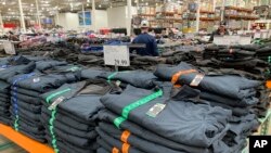 Shoppers peruse tables covered with stacks of weatherproof jackets in a Costco warehouse Thursday, Nov. 11, 2021, in Sheridan, Colorado.