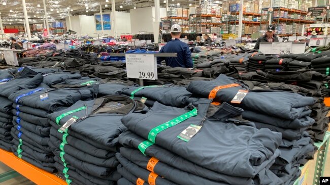 Shoppers peruse tables covered with stacks of weatherproof jackets in a Costco warehouse Thursday, Nov. 11, 2021, in Sheridan, Colorado.