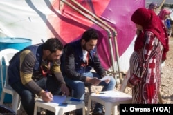 A Syrian women registers her details ahead of collecting items provided to help protect the refugees' makeshift shelters against the elements this winter.