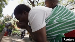 A Zimbabwean woman drinks water from a tap in Harare, May 4, 2010. 